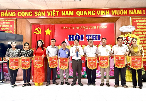 Đồng chí Nguyễn Mạnh Hà, Phó Trưởng Ban Tuyên giáo và Dân vận Tỉnh uỷ An Giang, trao cờ lưu niệm cho đại diện các đơn vị có thí sinh tham gia Hội thi Tuyên truyền viên giỏi phường Vĩnh Thông năm 2026. Ảnh: MT